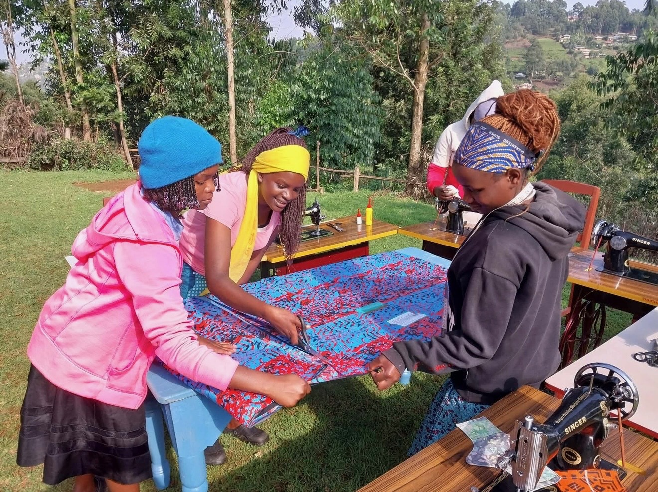 Young women measuring and cutting fabric together at the Dignity Sewing Center