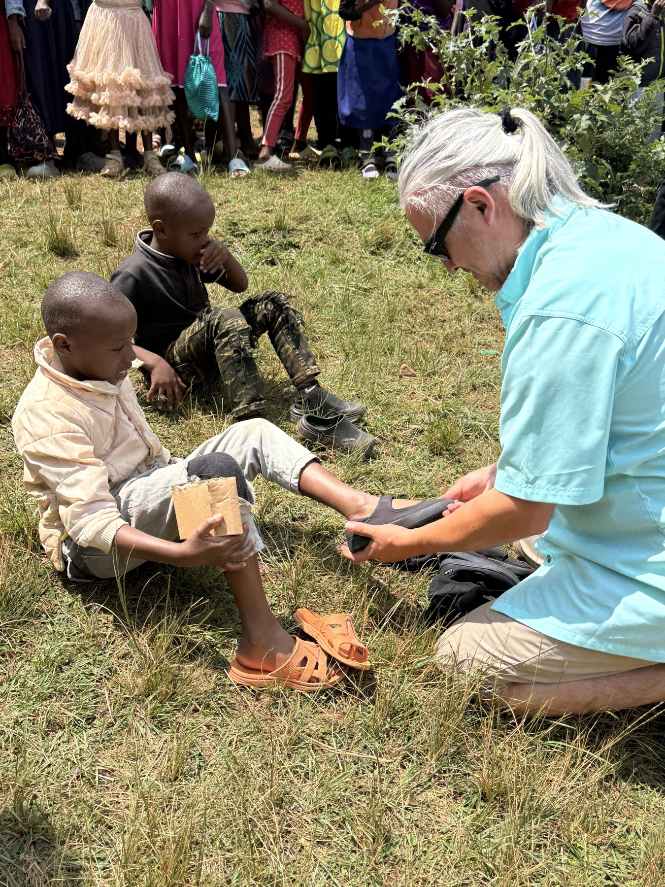 A Life Together Alliance supporter helping a child with a new pair of shoes
