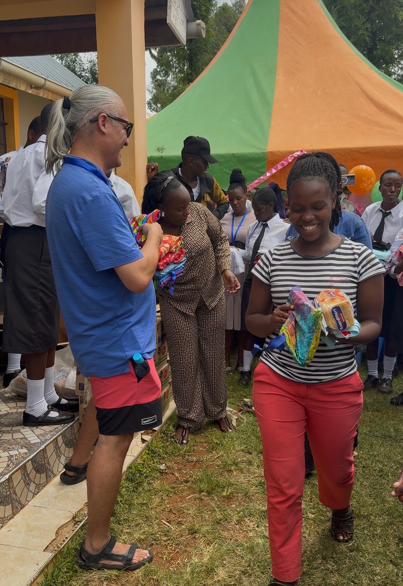 A young woman receiving a DignityKit and food during a community distribution