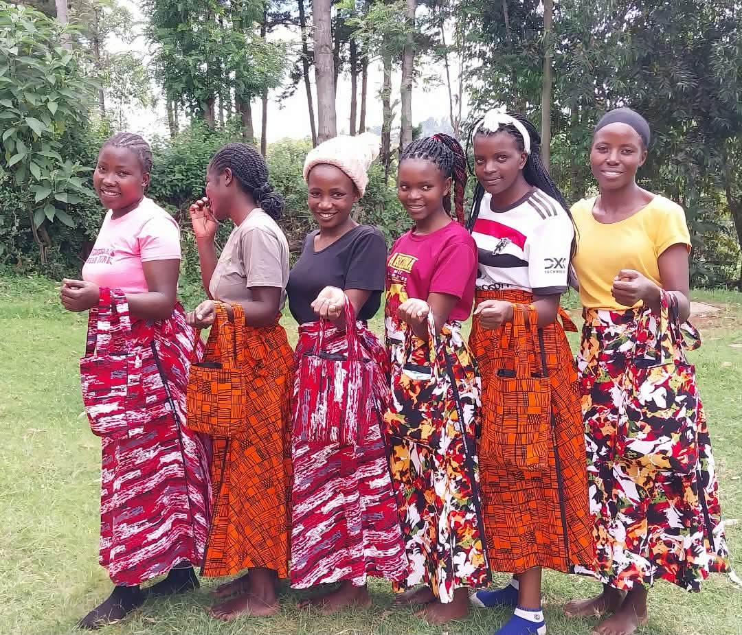 Young women displaying clothing and bags created through the sewing program